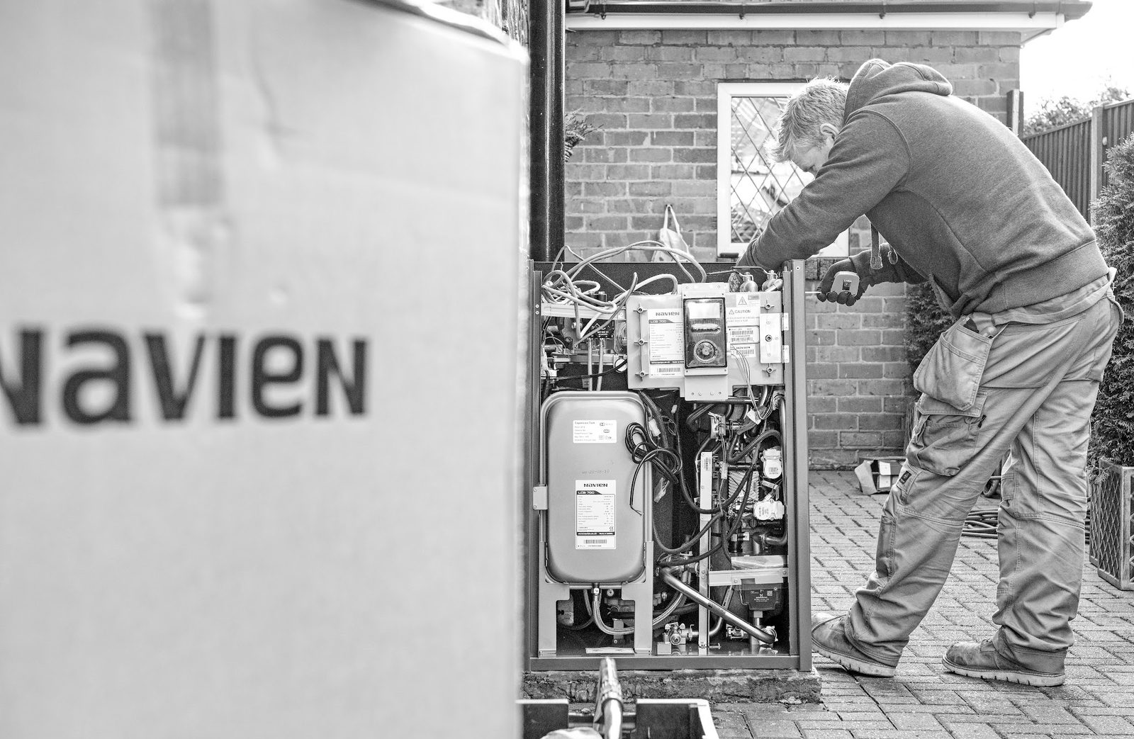 James working inside an open outdoor Navien boiler, in black and white
