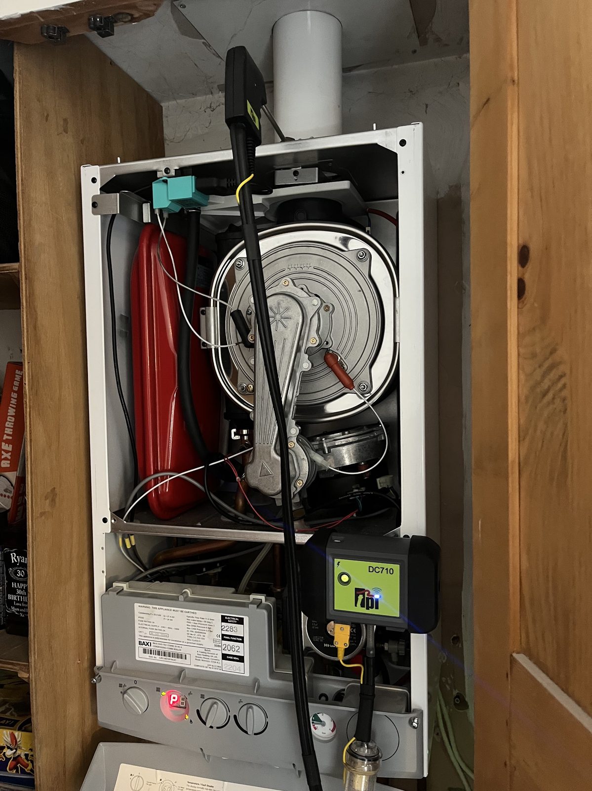 A wall-hung boiler opened up for a service with a combustion analyser connected