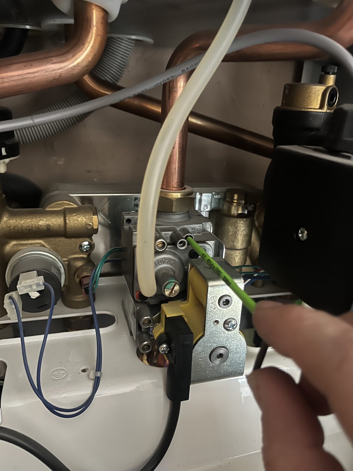 Close-up of a gas valve and pipework inside a boiler during a service