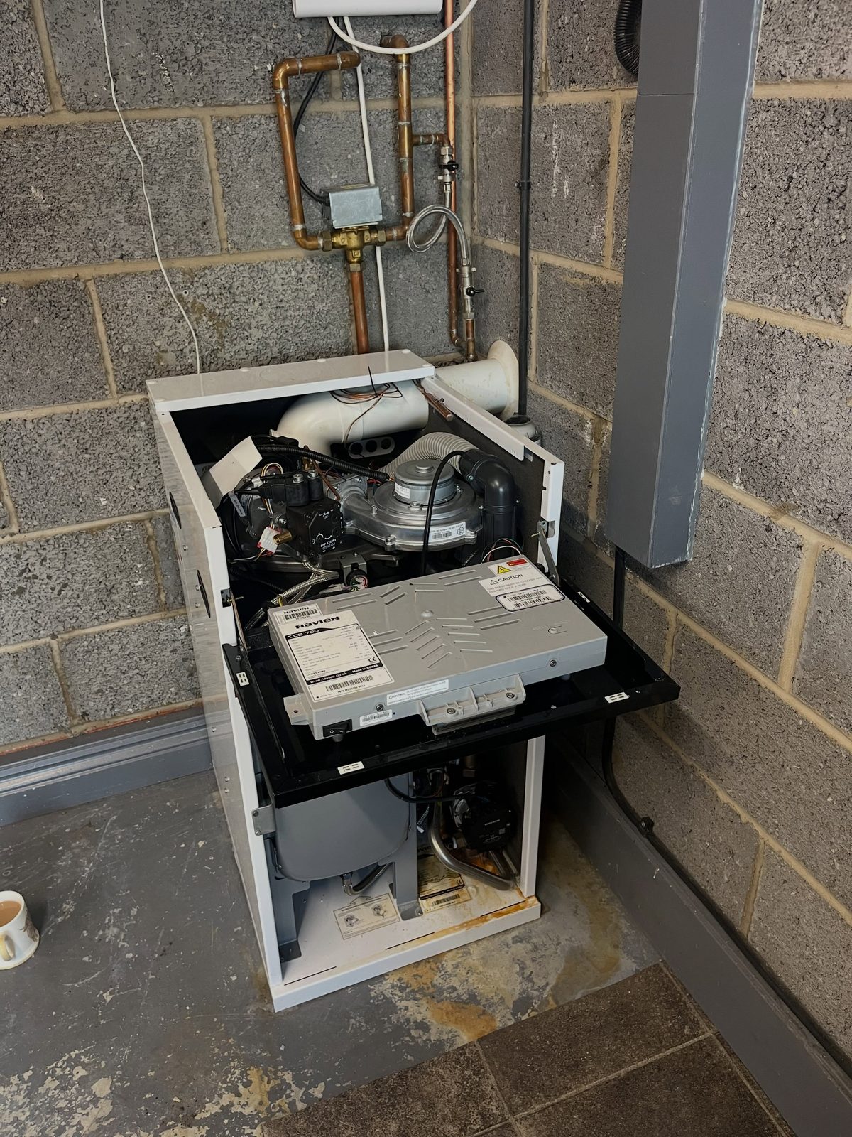 A Navien oil boiler raised on a plinth with its casing open